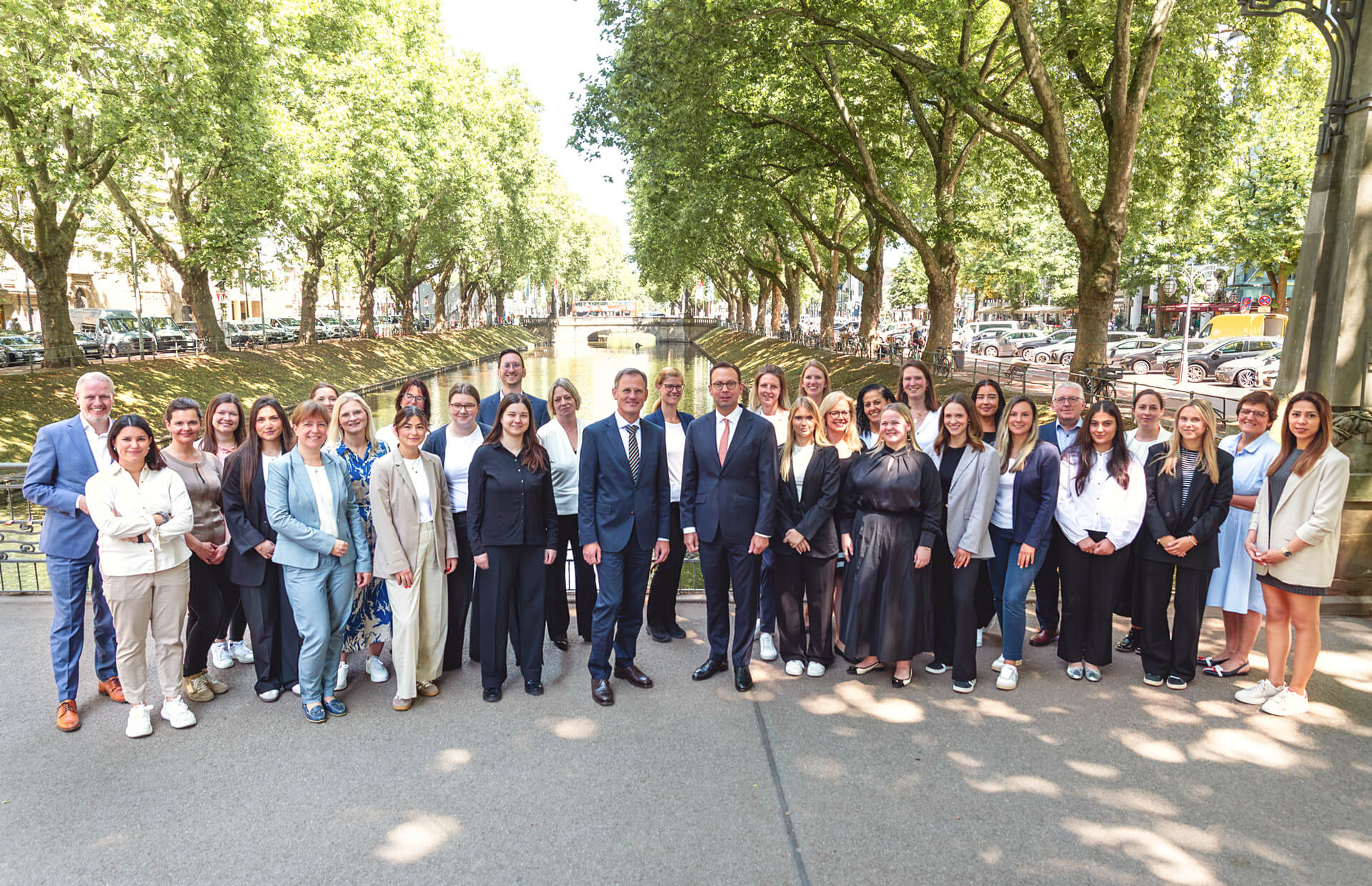Das gesamte Team des Notariats auf einer Brücke an der Königsallee in Düsseldorf